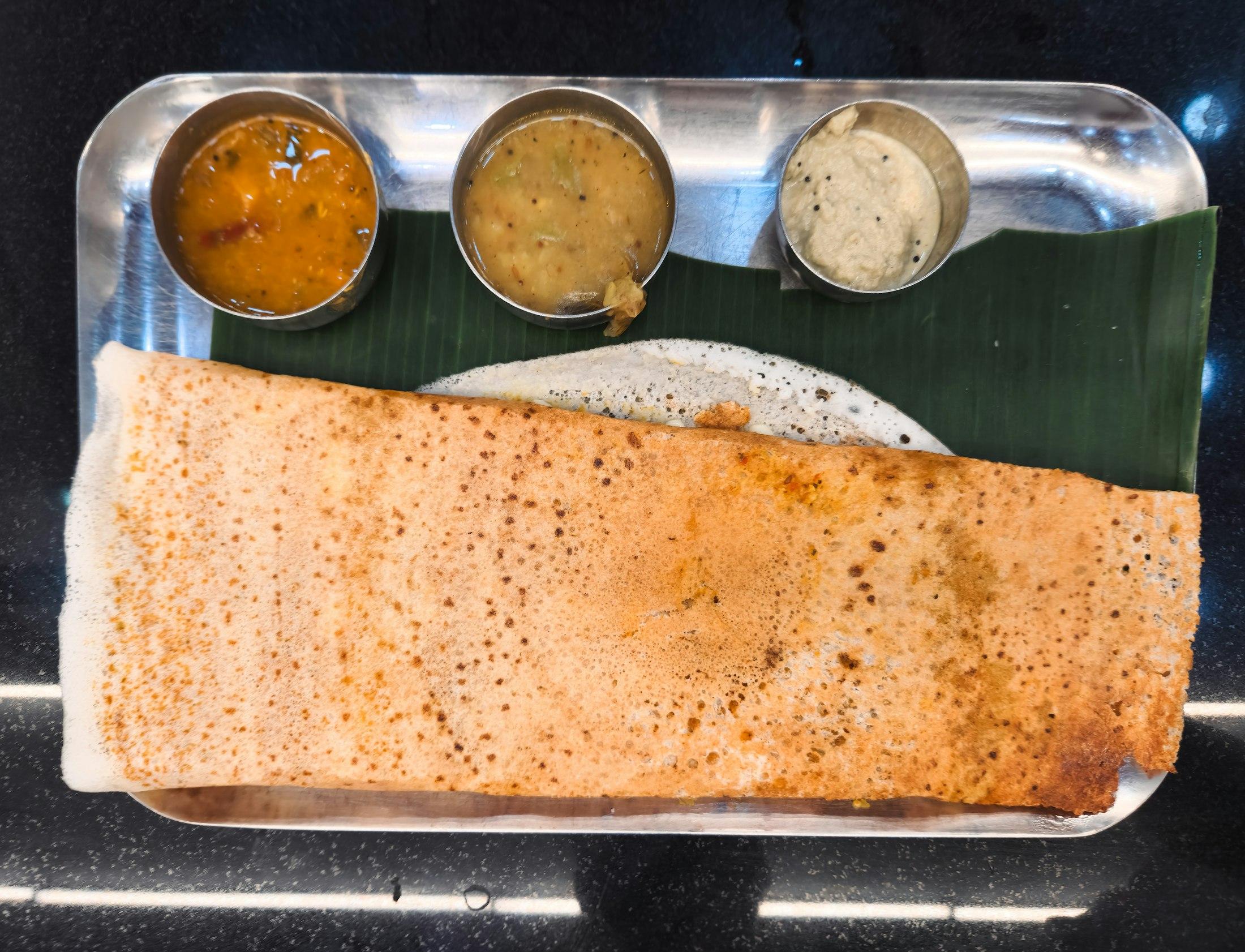 Crisp dosa with sambar and chutneys on a banana leaf